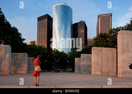 USA, New York, New York City, Young woman stands waiting beneath skyline in lower Manhattan at sunset on spring evening Stock Photo