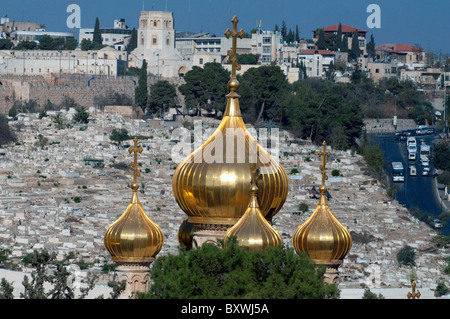 These are the golden domes of the Church of St. Mary Magdalene, with the city and walls of Jerusalem in the background. Stock Photo