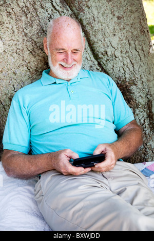 Senior man text messaging on his new smart phone. Stock Photo