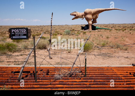 USA, Arizona, Holbrook, Sculpture of fighting dinosaurs on dusty desert road in desert near historic Route 66 on summer morning Stock Photo