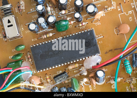 Integrated circuit or silicon chip on an early to mid 1990s era electronic circuit board with components such as resistors Stock Photo