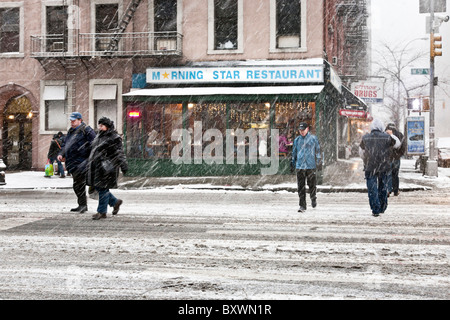 warmly dressed pedestrians cross 57th Street as driving blowing snow falls during December 2010 blizzard New York City Stock Photo