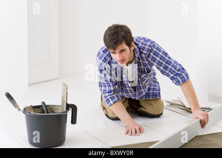 Home tile improvement - handyman with level laying down tile floor Stock Photo