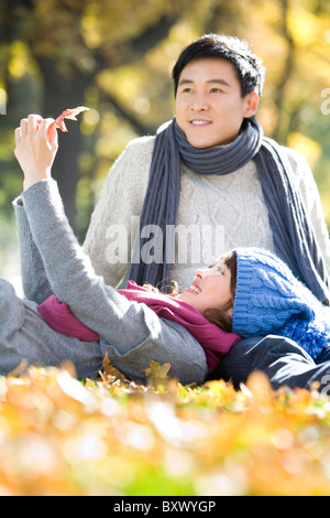 Young Couple in the Park Looking at a Maple Leaf Stock Photo