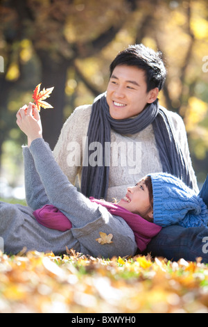 Young Couple in the Park Looking at a Maple Leaf Stock Photo