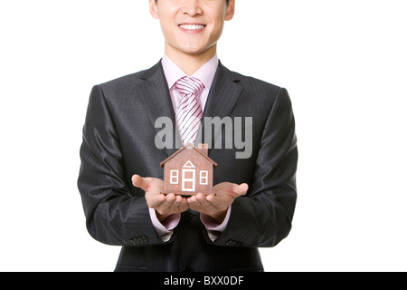 Businessman holding a small wooden model home Stock Photo