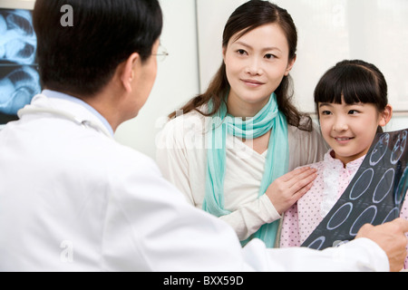Doctor discussing the results of an MRI scan with a young patient and her mother Stock Photo