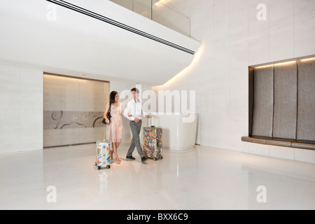 Young Couple with Luggage in Hotel Lobby Stock Photo