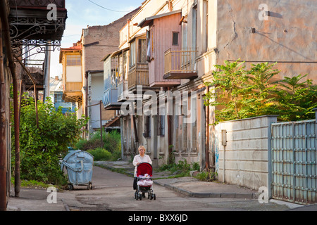 Woman pushing pram in street of typical balconied houses in Tbilisi old town, Kala, Georgia. JMH4029 Stock Photo