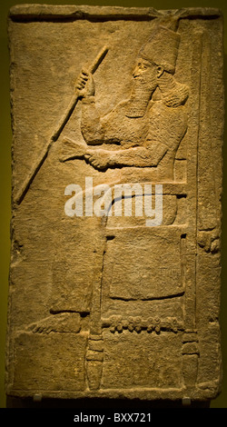 Neo-Assyrian limestone wall relief panel depicting King Tiglath-Pileser III seated on his throne holding ceremonial staff,Nimrud (Kalhu) circa 735 BC Stock Photo