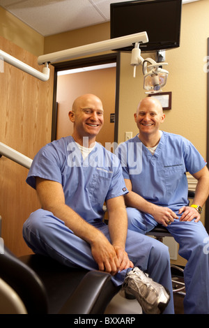 Dentists who are identical twins pose in an examining room in the clinic where they practice together in Austin, Texas USA. Stock Photo