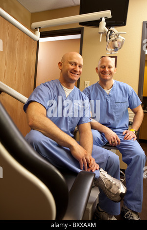 Dentists who are identical twins pose in an examining room in the clinic where they practice together in Austin, Texas USA Stock Photo