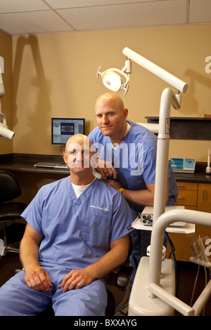 Dentists who are identical twins pose in a treatment room in the clinic where they practice together in Austin, Texas USA. Stock Photo