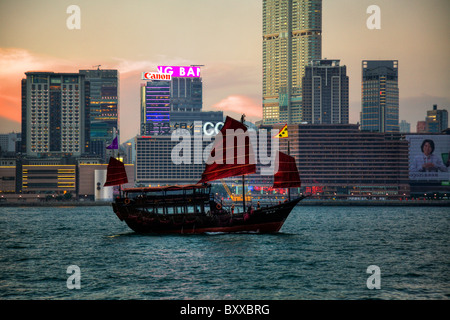 The Kowloon skyline at dusk showing the iconic red sail junk from Hong Kong Island, Hong Kong Junk boat, hong kong junk, bat wing boat, bat wing junk Stock Photo