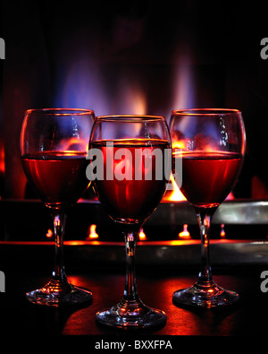 Wine glasses in front of a flame fire red wine cranberry juice warm fire winter warmth toast celebrate party New Year festive Stock Photo