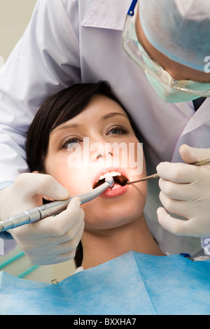 Close-up of young female with open mouth at the dentist office while doctor examining her oral cavity Stock Photo