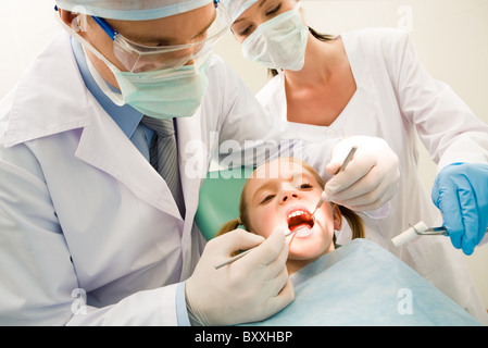 Image of dental checkup being given to little girl by dentist with assistant near by Stock Photo