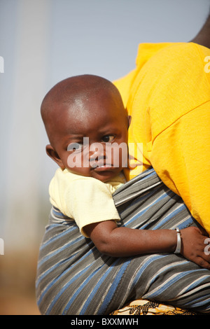 In the town of Djibo in northern Burkina Faso, a woman carries her young child strapped to her back. Stock Photo