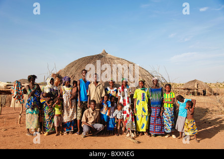 In the Fulani village of Jolooga in northern Burkina Faso, villagers stand outside a traditional house made from straw. Stock Photo