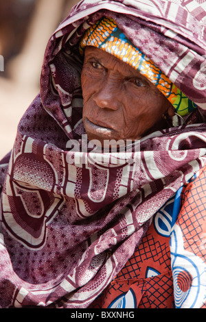 In the town of Djibo in northern Burkina Faso, an elderly Fulani woman pauses in the market to purchase greens for dinner. Stock Photo