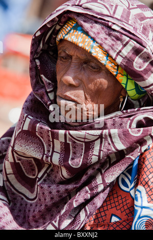 In the town of Djibo in northern Burkina Faso, an elderly Fulani woman pauses in the market to purchase greens for dinner. Stock Photo