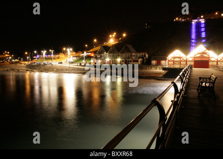 Looking down Saltburn Pier at night with a view of the illuminated cliff lift & local businesses. Stock Photo