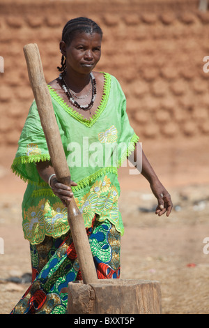 A Fulani woman in the town of Djibo in northern Burkina Faso pounds millet grain to make flour. Stock Photo