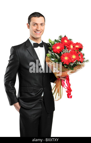 A man holding out large bouquet of gerberas in formal black tux with bow tie Stock Photo