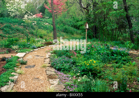 Spring awakens the garden as color replaces and fills in with new growth - spring flowers welcome you down the path Stock Photo