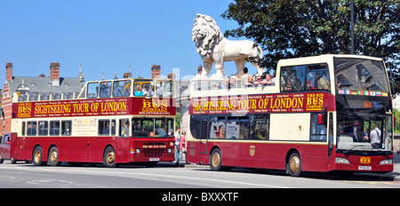 London street scene two open top sightseeing tour buses at bus stop on Westminster Bridge beside The South Bank Lion Coade stone sculpture England UK Stock Photo