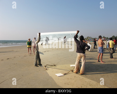 A worker guards a giant mirror on Majorda Beach, Goa, India which was being readied for the production of a Bollywood Movie bei Stock Photo