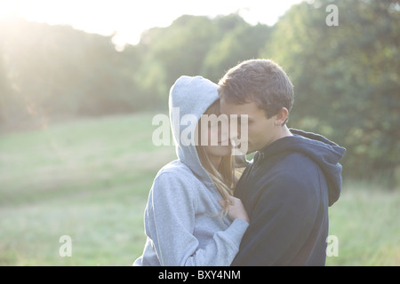 A young couple embracing outdoors, wearing hooded sweatshirts Stock Photo