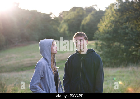 A young couple standing outdoors, wearing hooded sweatshirts Stock Photo