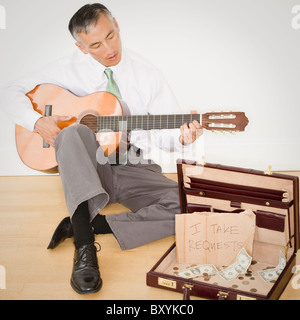 Businessman playing guitar in office Stock Photo