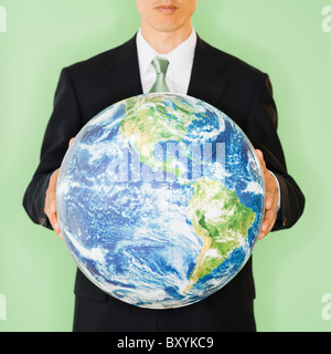Businessman holding globe, studio shot Stock Photo