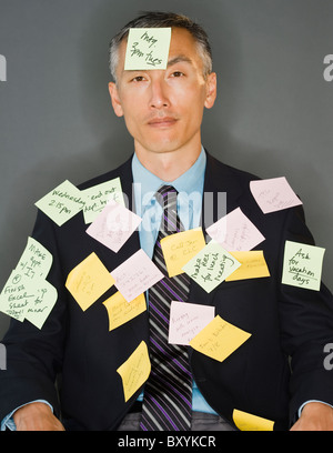 Businessman with post-it sticking on him, studio shot Stock Photo