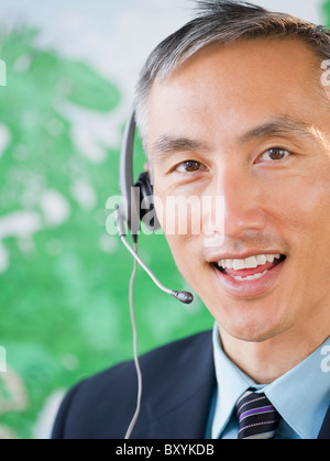 Businessman with headset looking at camera and smiling, studio shot Stock Photo