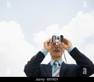 Businessman looking away through binoculars Stock Photo