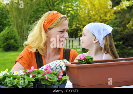 Young woman and her child potting flowers Stock Photo