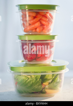Carrots, strawberries and salad in plastic containers, studio shot Stock Photo