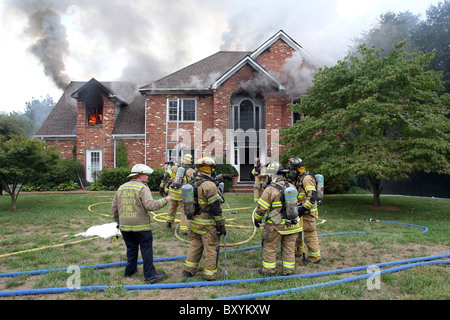 Fire fighters put out a blaze in a 2 story house. Stock Photo