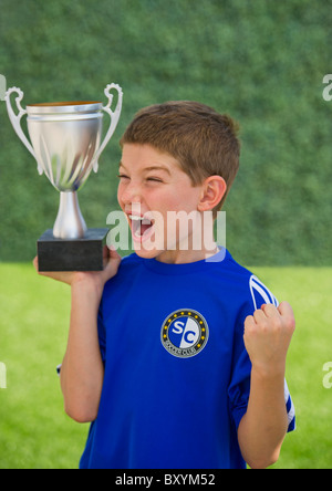 Boy holding trophy and cheering Stock Photo