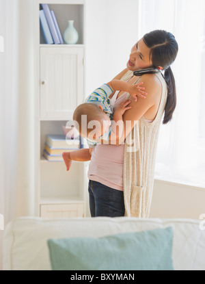 Mother carrying son and talking on phone Stock Photo