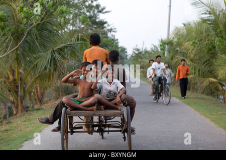 Children hitching a ride on a cycle rickshaw Stock Photo