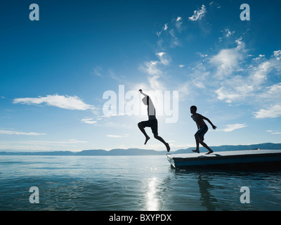 Boys jumping from raft Stock Photo