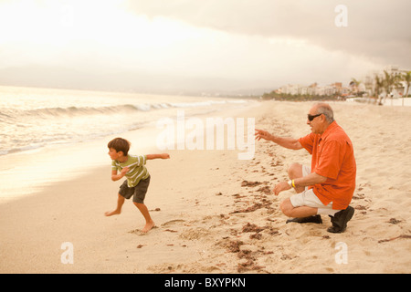 Grandfather and grandson playing on beach together Stock Photo