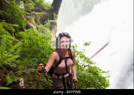 Hispanic woman hiking in woods near waterfall Stock Photo