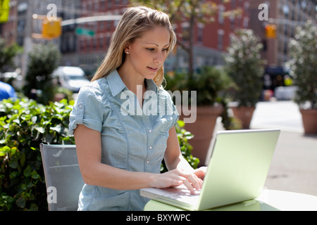 Young woman using laptop at pavement cafe Stock Photo