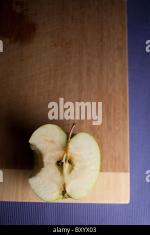 Sliced Granny Smith apple with a bite taken out of it on a wooden cutting board Stock Photo