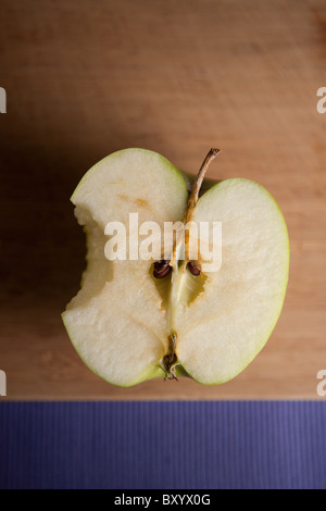 Sliced Granny Smith apple with a bite taken out of it on a wooden cutting board Stock Photo